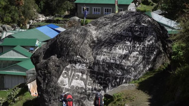 Tourists are near prayer stone in Nepal. Traditional prayer stone with a Buddhist mantra: om mani padme hum. Translation: Pearl in a lotus flower! Nepal. 4K