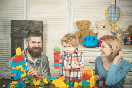 Father, mother and son in playroom on light wooden background.