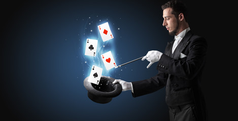 Magician making trick with wand and playing cards