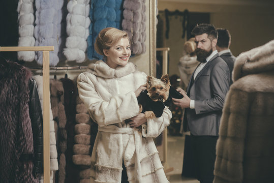 Woman in fur coat with dog and man in shop.