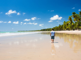 man walking along beach view on a summer day