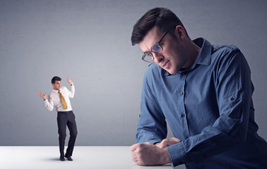 Young businessman fighting with miniature businessman