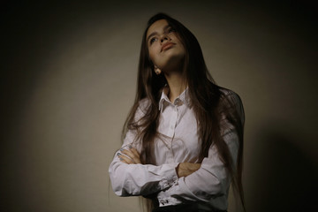 Portrait of a young adult woman in a white shirt thoughtful