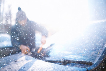 man cleans snow from cars