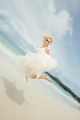 Naklejka premium happy bride jumping in wedding dress at the sea. young happy woman on beach.