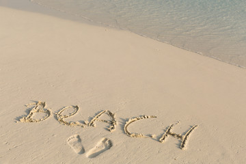 Handwritting inscription word BEACH on sand