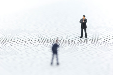 Miniature people: Businessman standing on start point of maze using as background business concept.