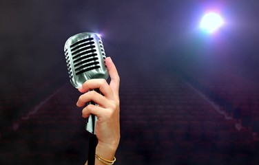 hand holding retro microphone on stage under spotlights