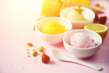 Red, pink, yellow, green, white ice cream balls in bowls, waffle cones, berries, orange, mango, lemon, mint, pistachio, pink shabby chic background. Ice-cream colorful collection, summer concept