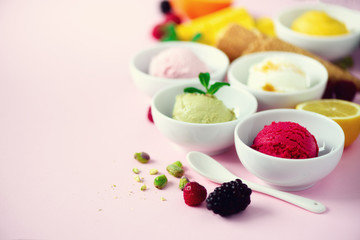 Red, pink, yellow, green, white ice cream balls in bowls, waffle cones, berries, orange, mango, lemon, mint, pistachio, pink shabby chic background. Ice-cream colorful collection, summer concept