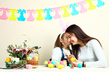 Naklejka premium Mother and little daughter coloring Easter eggs