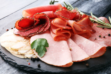 Food tray with delicious salami, pieces of sliced ham, sausage, tomatoes, salad and vegetable - Meat platter with selection