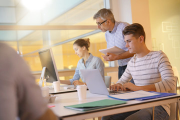 Teacher with students in apprenticeship attending computing class