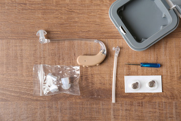 Composition with hearing aid and accessories on wooden background