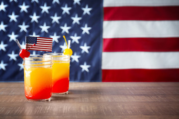 Jars with alcoholic cocktail on table against American flag background