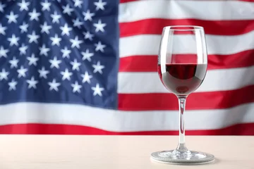 Poster Vin Glass of wine on table against American flag background
