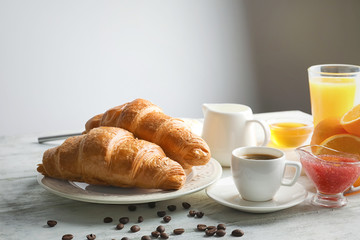 Plate with tasty croissants and cup of coffee on table