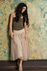 Fototapeta premium Brunette Woman on Vintage Green Wall Background. Fashion Photo