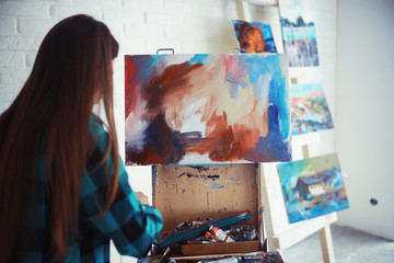 Young artist girl at work in the workshop brush paints canvas inspiration