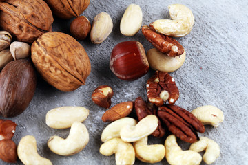 mixed nuts on grey background. Healthy food and snack. Walnut, pecan, almonds, hazelnuts and cashews.