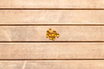 Fototapeta premium A few pills scattered on a wooden table . On a brown background