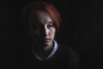 a girl is sitting and sad outside the window in rainy weather