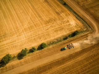 Fototapeta premium Aerial view of a tractor working a field after harvest
