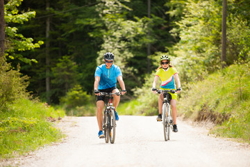 ACTIVE Young couple biking on a forest road in mountain on a spring day