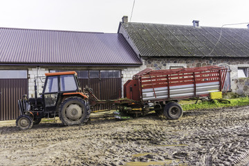 A tractor with a large trailer. The trailer is a rotary mower for various grasses. Late autumn. Podlasie, Poland.