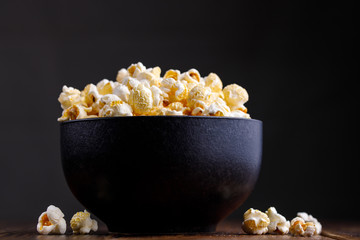 Popcorn in a ceramic bowl on a wooden background.