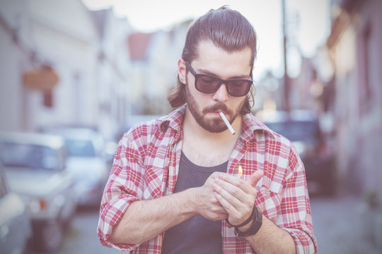 Young man with cigarette posing on the street.