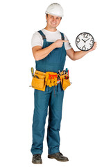 builder in a helmet holding big clock and looking at camera over white wall background. repair, construction, building, people and maintenance concept.