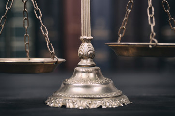  Scales of Justice on a black wooden background.