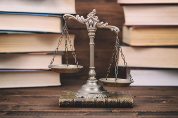  Scales of Justice and law books on a wooden background.