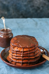 Chocolate pancakes wiyh syrup in a plate on a blue background.