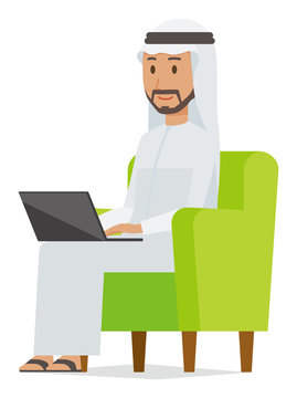 An arab man wearing ethnic costumes is sitting on a sofa and operating a laptop computer