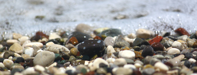 Pebbles by sea on beach, for banner and texture. Focus runs through the middle