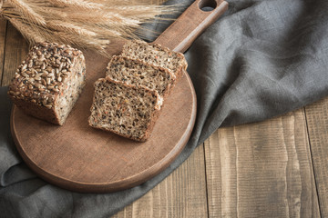 Loaf of fitness rye bread with ears of wheat, sliced on cutting board. Close up. Copy space.