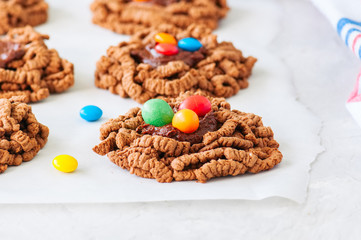 Chocolate bird's nest cookies with ganache and decorated with colorful candies on a white background.