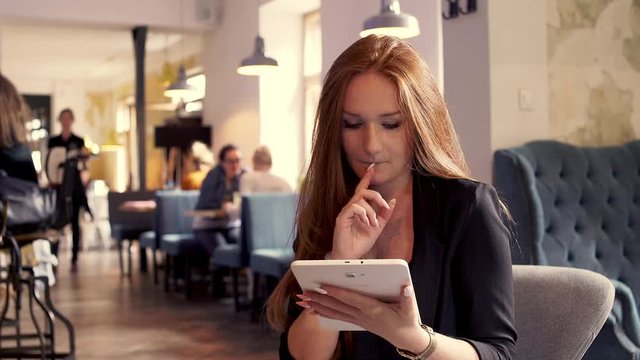 Young beautiful businesswoman sitting withn tablet in cafe
