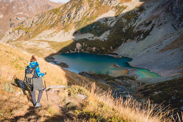 Fototapeta premium Woman hiker in the mountains and lake at background. Tourist woman descend from the mountain