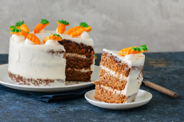 Carrot cake with cream cheese frosting decorated with carrot marmalade serving on a plate on a blue stone background. - 195128669