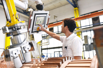 young mechanical engineering workers operate a machine for winding copper wire - manufacture of transformers in a factory - obrazy, fototapety, plakaty