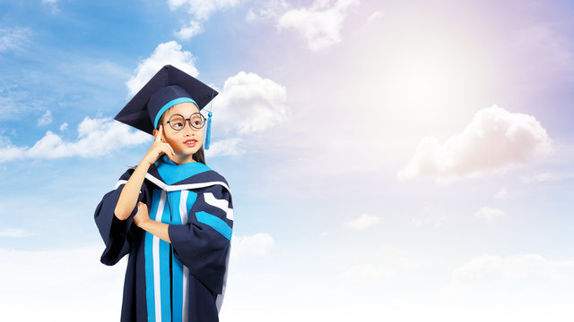 Little girl graduate thinking pose with in the sky background.Clipping path