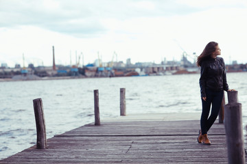 Young adult woman sitting on a wooden jetty on the river