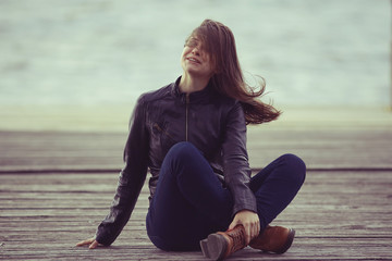 Fototapeta na wymiar girl in a leather jacket sits outside the rustic style
