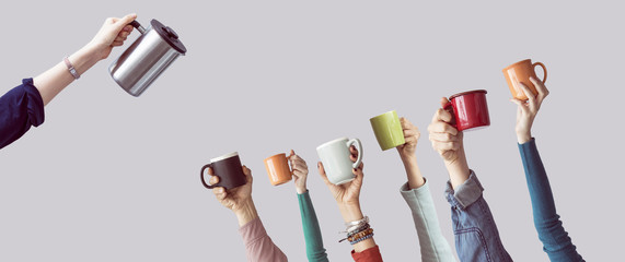 Many different arms raised up holding coffee cup