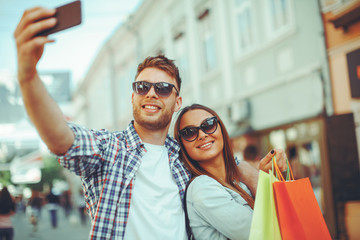 Attractive young couple doing selfie after shopping in european city