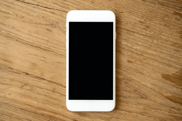 Mockup image of white mobile phone with blank black screen on vintage wooden table background