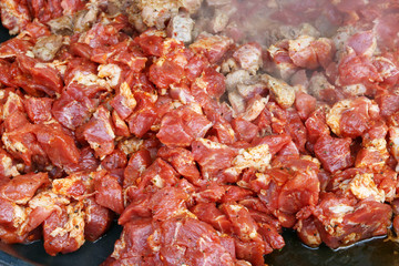 Obraz na płótnie Canvas Pieces of pork meat in red chili sauce are fried in a frying pan